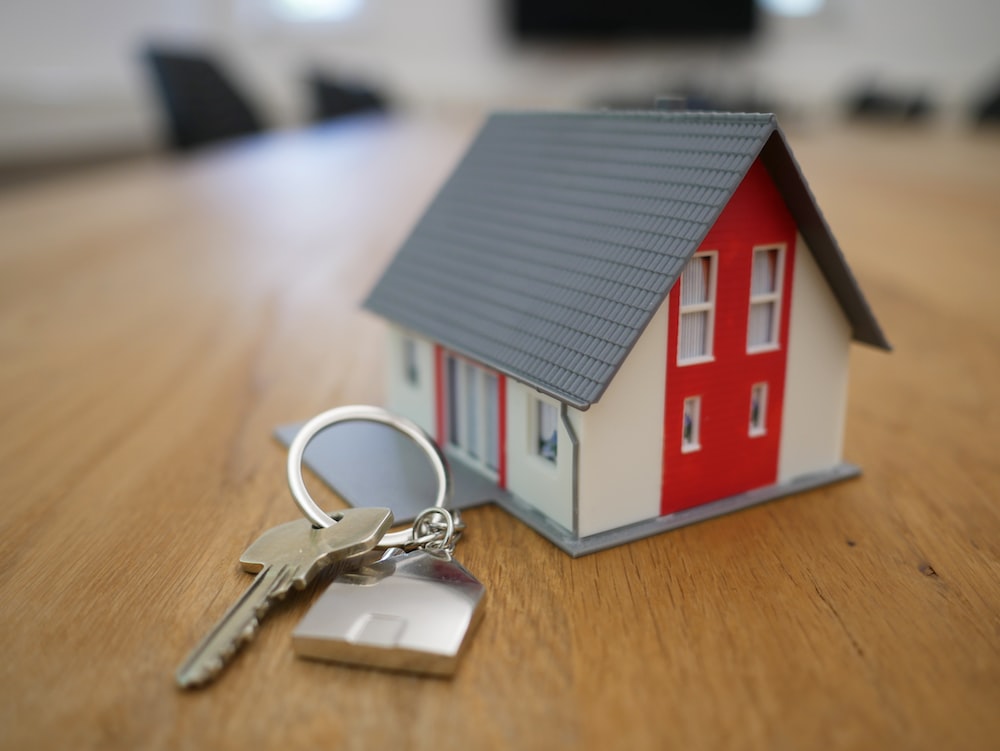 image of toy house next to keys on a table